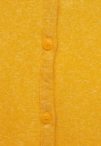 Cardigan jaune avec un motif de tricot texturé. Présente des boutons ronds assortis et une vue rapprochée du pli avant.