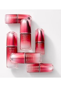 Seks Shiseido Ultimune Power Infusing Concentrate flasker arrangeret med et gradient rød og klar design, med en rund kappe og en glat tekstur.