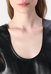 Black leather top with a wide scoop neckline and smooth texture, featuring slight sheen and subtle accents around armholes.