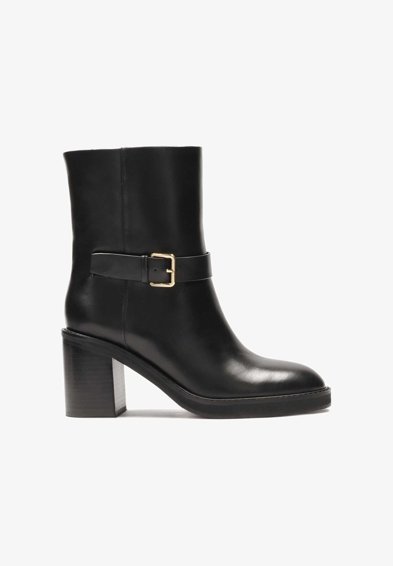 Botín de cuero negro hasta el tobillo con punta redondeada, un acento de hebilla dorada en la correa y un tacón en bloque grueso. Textura suave con un diseño minimalista.