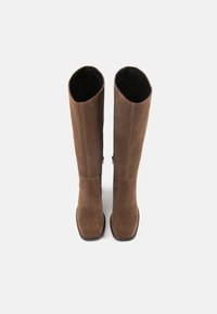 Cizme din suede maro, până la genunchi, cu o textură netedă, vârful pătrat și detalii de cusătură minime. Interiorul este de culoare neagră, cu un finisaj curat.