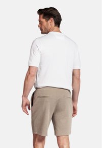 Witte kortefrishem shirt en beige shorts. Het shirt heeft een subtiel logo op de achterkant. De shorts hebben twee achterzakken. Soepele stoftextuur.