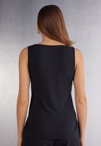 Svart ärmlös topp i slätt material, med rund halsringning och en figurnära design utan synliga sömmar eller mönster.