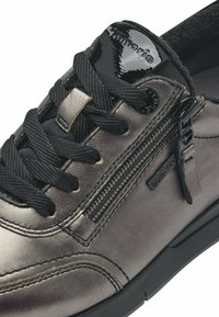 Metallisch grauer Sneaker mit schwarzen Schnürsenkeln, Reißverschluss und strukturiertem Obermaterial. Verfügt über einen glänzenden schwarzen Lackakzent an der Ferse und ein Logodetail.