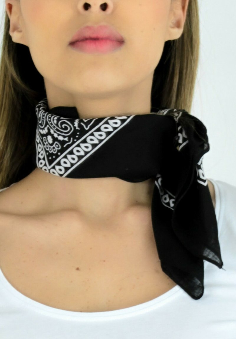 Écharpe en soie noire avec un motif paisley blanc, nouée autour du cou. L'écharpe a une texture lisse et une forme carrée.