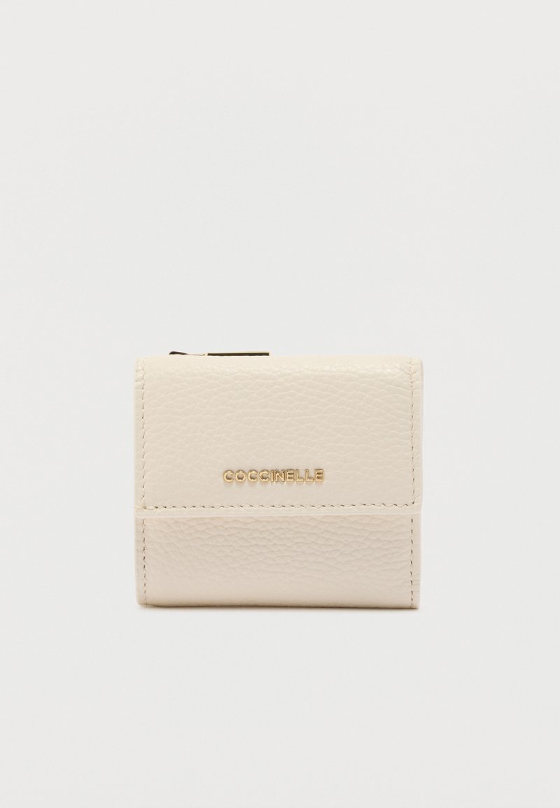 Συμπαγές πορτοφόλι από κρεμ δέρμα με υφή και χρυσό λογότυπο COCCINELLE στο μπροστινό καπάκι, σε απλό φόντο.