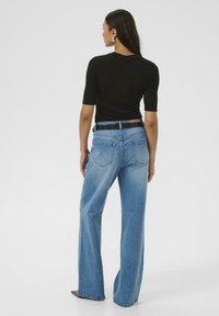 Hoge taille blauwe denim jeans met een rechte pijp, voorzien van twee achterzakken en een gestructureerde stof. Draagt een aangesloten zwart shirt.