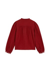Blusa rossa testurizzata con maniche lunghe e puff, schiena plissettata e colletto con volant. Presenta dettagli a bottone a contrasto nei polsini.