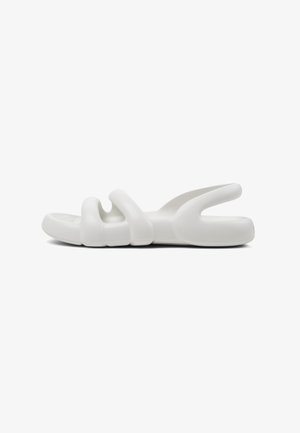 White slip-on sandals with a smooth, flexible plastic material. Features a unique design with three wave-like cutouts on the upper.
