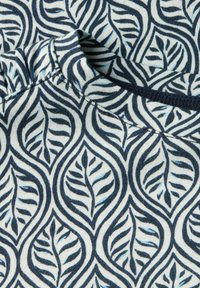 Bavlněná tkanina s námořnickým modrým a bílým vzorem listů se zakřivenými liniemi a detaily. Textura je měkká a žebrovaná.