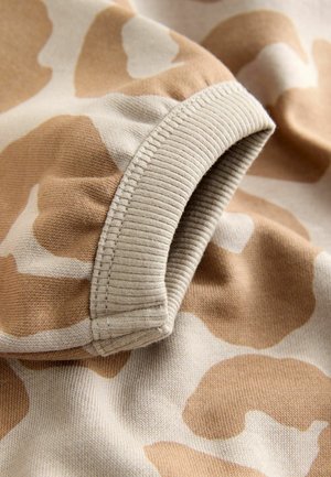 Kamo mustriga kangas sisaldab beeži ja pruuni laiku. Varre ääres on ribakujuline tekstuur, mille serval on selged õmblused.