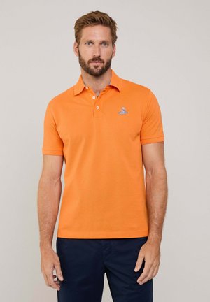 Camiseta polo naranja hecha de algodón, con cuello y mangas cortas. Incluye un pequeño logo azul bordado en el pecho.