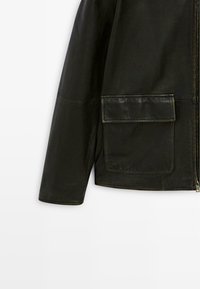 Black leather jacket with a zipped front, long sleeves, and a large, patch-style pocket on the left side. Smooth texture with minimal seams.