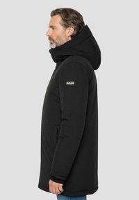 Sort hættejakke i dun med lynlås, sidelommer og et logo på venstre ærme. Glat, isolerende materiale.