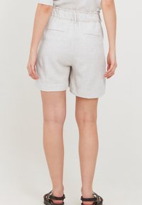 Pantaloni corti in lino grigio chiaro con una cintura elasticizzata, tasche laterali e un taglio rilassato, realizzati in un tessuto testurizzato e con una lunghezza sopra il ginocchio.