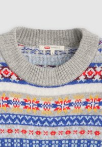 Grijze gebreide trui met meerkleurige patroonbanden in blauw, rood en geel. Ronde geribbelde kraag met label dat maat 'S' aangeeft.