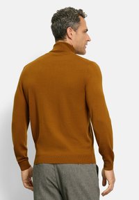 Brauner gerippter Rollkragenpullover mit langen Ärmeln, aus weichem Material gefertigt, mit figurbetontem Schnitt und hohem Kragen.