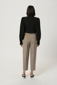 Haut noir côtelé à manches longues avec épaules bouffantes; pantalon écru à rayures verticales taille haute; sandales noires à talons avec une bride.