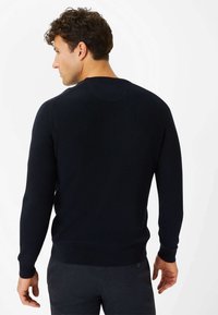 Marineblauer Strickpullover mit langen Ärmeln, gerippter Textur, rundem Ausschnitt und schmalem Saum. Verfügt über ein glattes, einheitliches Erscheinungsbild.