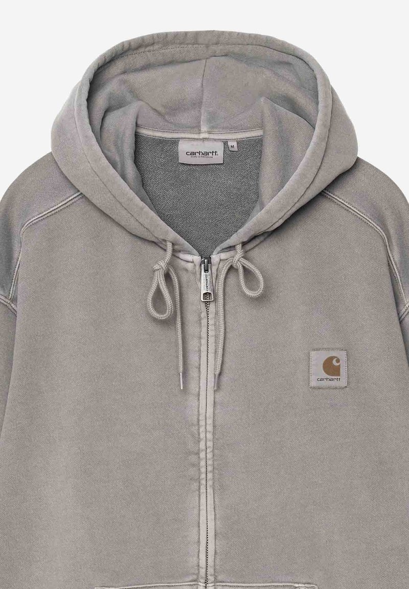 Sweat à capuche gris clair zippé avec cordons, patch logo Carhartt sur la poitrine et une étiquette à l'intérieur du col indiquant la taille M.