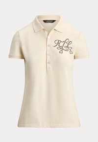 Polo tričko vo svetlom béžovom s golierom, krátkymi rukávmi, zapínaním na päť gombíkov a vyšívaným logom zo strieborného vlákna na hrudi.