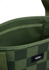 Groene geruite stoftas met een gestructureerde vorm, een binnenzak en een zwarte logo patch. Stevige handvatten en versterkte stiknaden.