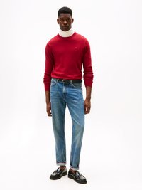 Maglione lavorato a maglia rosso, colletto alto bianco, jeans blu chiaro a gamba dritta, mocassini neri con dettagli decorativi, design minimalista, senza motivi visibili.