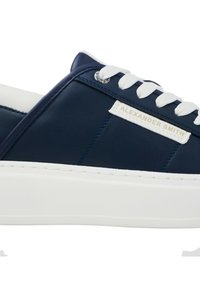 Sneaker in pelle blu con lacci bianchi, dotata di una suola bianca spessa, un design cucito e un patch con logo sul lato.