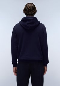 Felpa blu navy con cappuccio, polsini e orlo a coste, realizzata in materiale morbido. La vista posteriore mostra una texture liscia e un design minimalista.