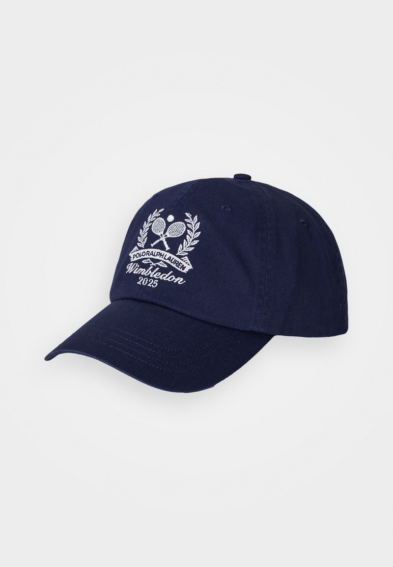 Casquette de baseball bleue marine en coton, avec un logo brodé blanc représentant des raquettes de tennis, un laurier et le texte "Wimbledon 2025". Visière ajustée.