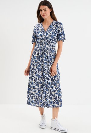 Floral-printed, blue and white midi dress with a V-neck, short sleeves, gathered waist, and lightweight fabric, paired with white sneakers.