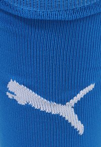 Μπλε αθλητική κάλτσα με ριμπ υφή, που διαθέτει το χαρακτηριστικό λευκό λογότυπο Puma πλεκτό στο ύφασμα. Κατάλληλη για αθλητικές δραστηριότητες και καθημερινή χρήση.