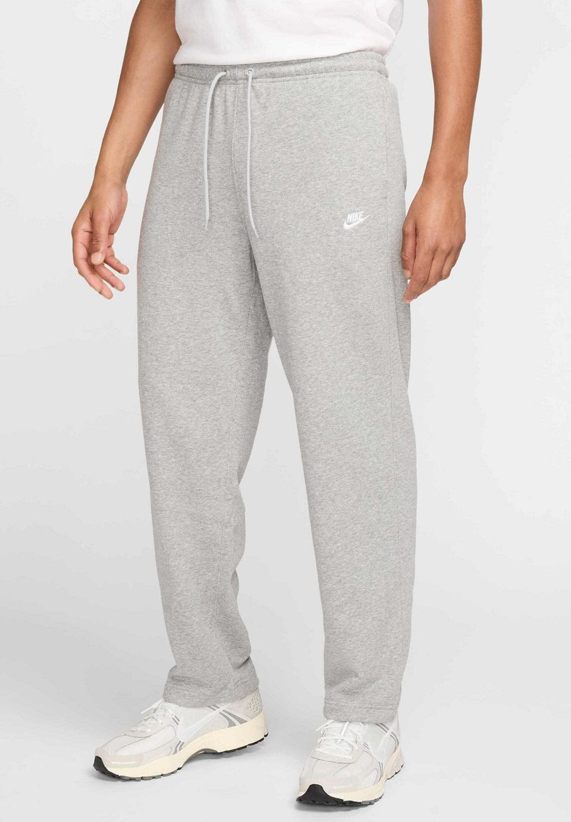 Pantalons de survêtement gris en tissu doux, avec une taille à cordon, des poches latérales et un petit logo Nike blanc sur la cuisse gauche.