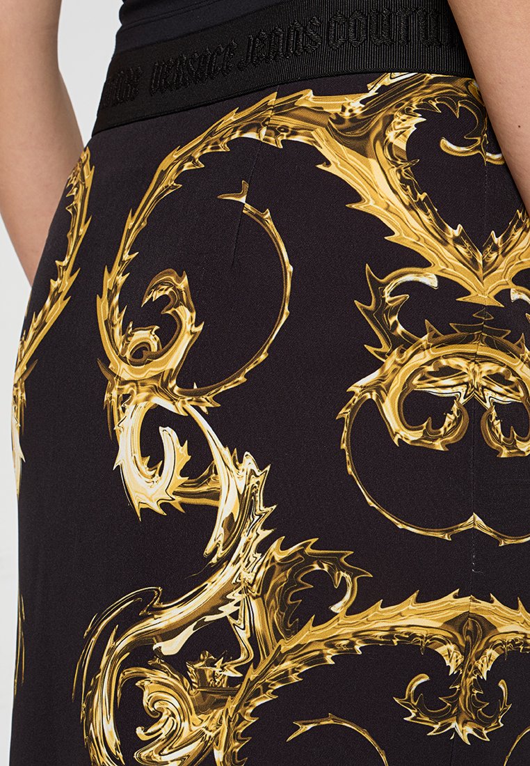 Gonna nera con ornate motivi barocchi in oro, indossata con un top nero che mostra una vita texture.