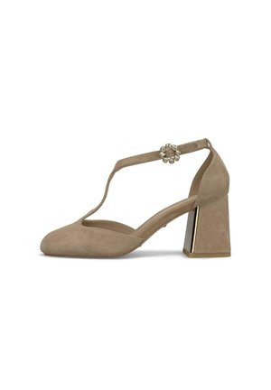 Zapato de tacón ancho para mujer de ante beige con tira en T y hebilla decorativa con piedras de strass sobre fondo blanco.