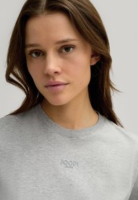 Grijze katoenen t-shirt met een ronde halslijn, voorzien van een lichtblauw geborduurd logo met de tekst "JOOP! JEANS" op de borst.