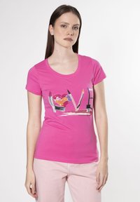 Camiseta de algodón rosa con mangas cortas que presenta un diseño gráfico de cosméticos y el texto "AMOR" adornado con detalles coloridos.