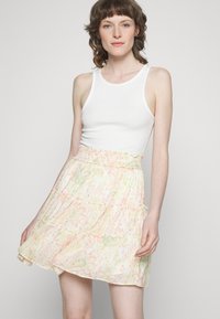 Saia com estampado floral em uma paleta de cores pastel; apresenta uma cintura empolesada, babados em camadas e um tecido leve e texturizado.