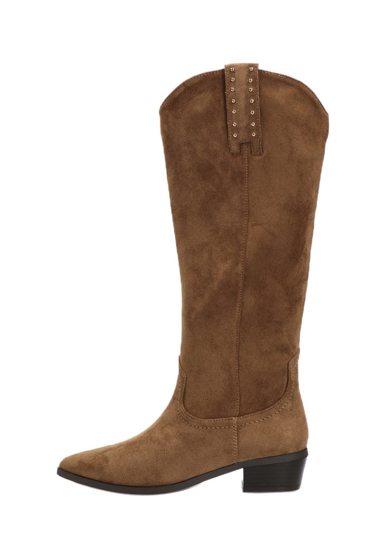 Botas marrones de ante sintético hasta la rodilla con punta afilada, tacón bajo y detalles decorativos de tachuelas en la parte trasera. Suela plana y textura suave.