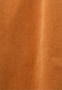 Gros plan d’un tissu en velours côtelé doux de couleur orange chaud avec une texture visible et des stries verticales.