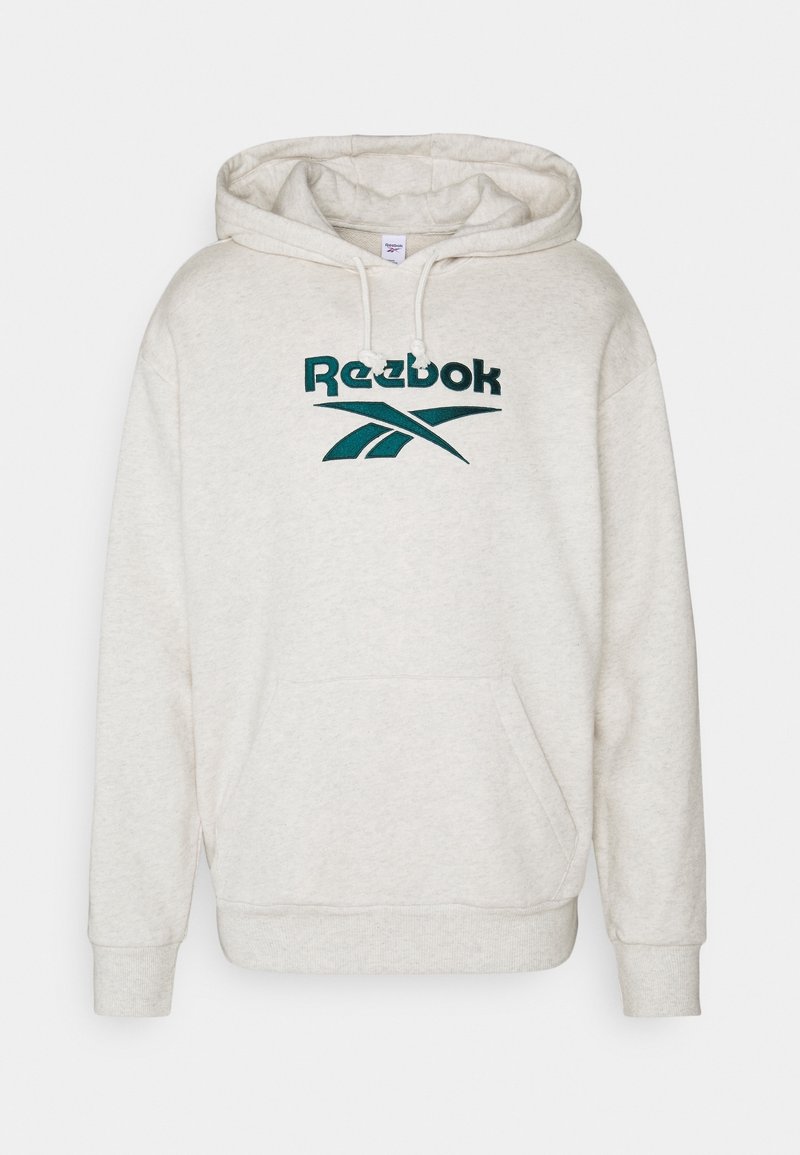 Sudadera Reebok de color gris claro con un bolsillo frontal, capucha con cordón y logo bordado en negro que presenta líneas entrelazadas. Textura de material suave.