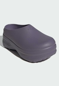 Zuecos morados fabricados con material plástico suave, con puntera redondeada y un detalle sutil del logotipo, que cuentan con una suela de agarre texturizada para mayor tracción.