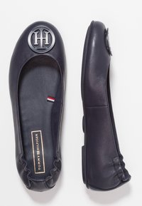 Granatowe skórzane baleriny z okrągłym noskiem, wyraźnym logo na czubku oraz teksturowanymi bokami; zawierają subtelny, prążkowany detal wewnątrz.