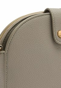 Borsa in pelle grigia a forma arrotondata, con zip dorata e accento con logo. Presenta una superficie testurizzata e bordi lisci.