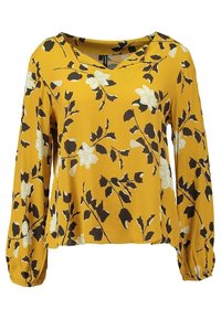 Blouse florale jaune à manches longues, ornée de feuilles noires et de fleurs blanches. Tissu doux, décolleté en V et poignets froncés.