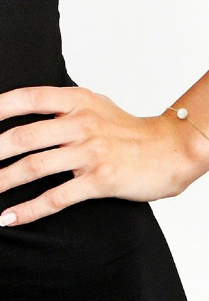 Bracelet en or avec une seule perle blanche. Le design présente une chaîne délicate et une perle ronde lisse avec une finition brillante.