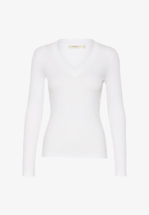 Fehér, hosszú ujjú felső bordás textúrával és V-nyakkivágással. Fitted fazonnal és finom varrás részletekkel a nyakán és az alján.