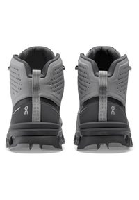 Gray high-top trail shoes with textured material, cushioned collar, reflective accents, and rugged black outsole with pronounced traction.
