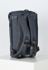 Sac à dos gris foncé avec des bretelles en mesh rembourrées, une poignée supérieure, une fermeture éclair latérale et des boucles réglables. Il se distingue par un design structuré et un tissu robuste.