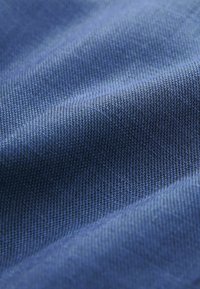 Sinine kangas, millel on sile, ühtlane tekstuur ja tihe koestruktuur, näidates pinna ulatuses erinevaid sinise toone. Muster ega riistvara puuduvad.